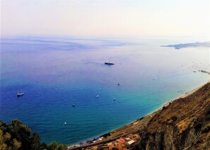 Un paisaje costero con vista despejada al mar, barcos y terreno montañoso.
