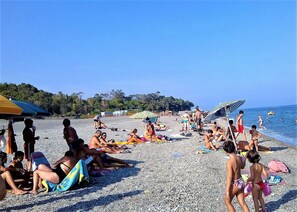 A crowded beach with people sunbathing and swimming.