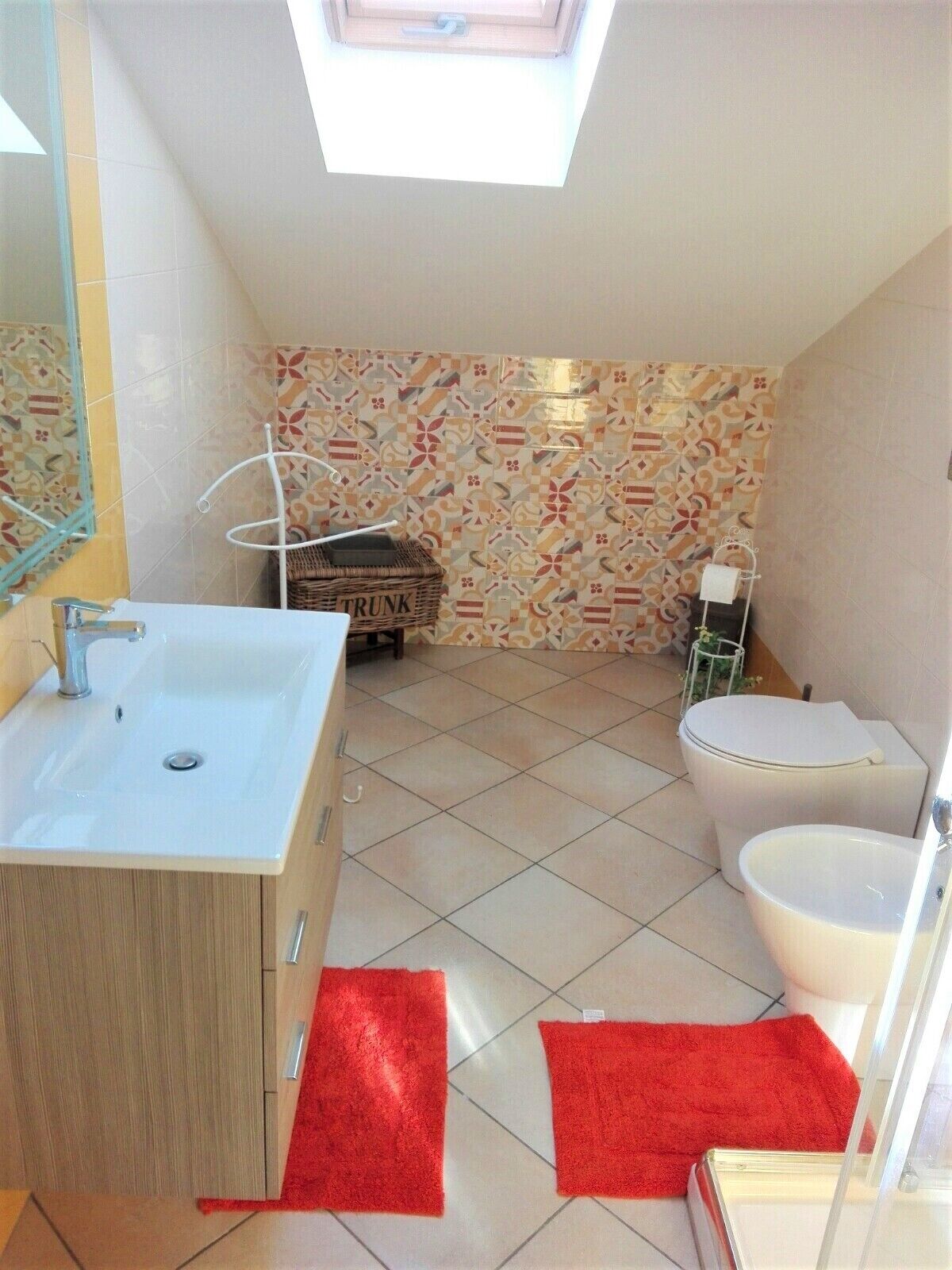 A bathroom with a skylight, a sink, a toilet, and a trash bin labeled "TRUNK".