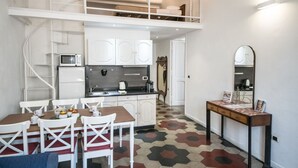 Une cuisine compacte avec des meubles blancs, un four à micro-ondes et un coin repas comprenant une table et des chaises.