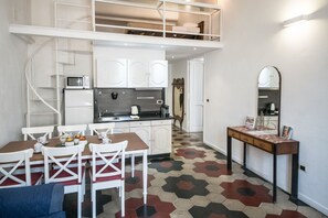 A compact kitchen with white cabinets, a microwave, and a dining area with a table and chairs.