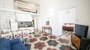 Un espace de vie compact comprenant un coin cuisine, un coin repas, un téléviseur et un lit.
