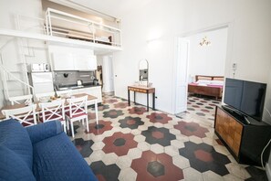 A compact living space with a kitchenette, a dining area, a TV, and a bed.