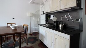 A kitchen with white cabinets, a black countertop, and a dining table with chairs. - Relax Apartment Navona Sq. (Roma)
