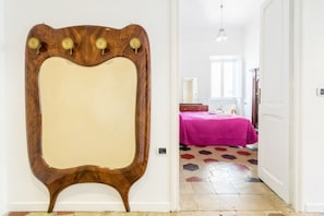 Ein Zimmer mit einem Holz-Waschtisch, einem Bett mit rosa Bettdecke und einem Boden mit geometrischem Muster.