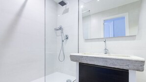 Une salle de bain moderne avec une douche à parois de verre, un lavabo en marbre et un grand miroir.