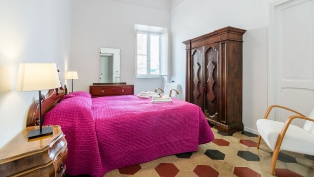 Une chambre à coucher avec un lit, une armoire en bois, un bureau avec une lampe, une chaise et une fenêtre.