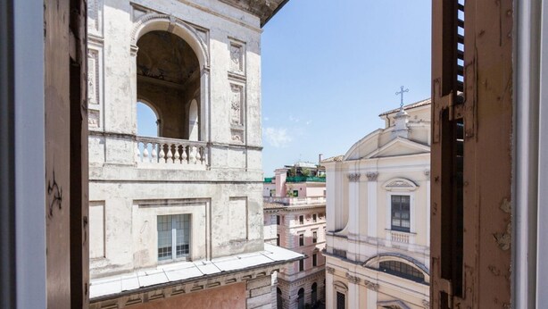 A view of a narrow street with historic buildings, including a building with a balcony and arched windows. - Relax Apartment Navona Sq. (Roma)