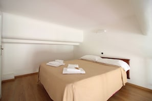 A bedroom with a bed, wooden floor, white walls, and a ceiling light. - Relax Apartment Navona Sq. (Roma)