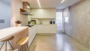 Cozinha moderna com bancada branca, banquetas e forno embutido.