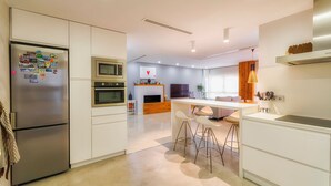 Uma cozinha moderna com geladeira, forno, micro-ondas e banquetas de bar.