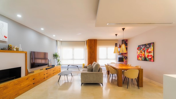 Sala de estar moderna com televisão, sofá, mesa de jantar e cadeiras.
