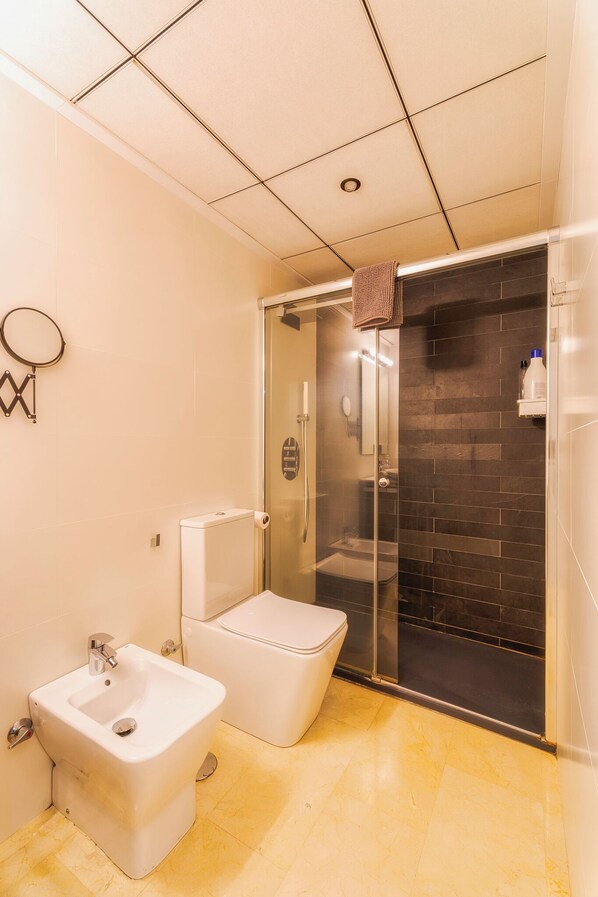 Een badkamer met een toilet, douchecabine en een bidet.