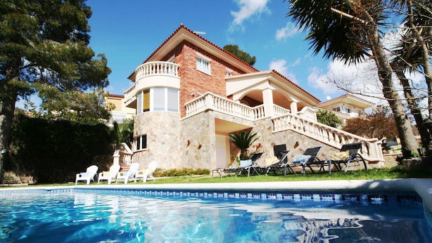 A large house with a swimming pool, a balcony, and a staircase leading to the upper floor.