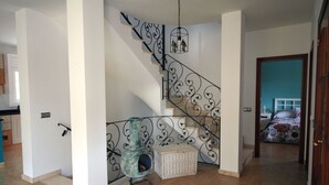 A staircase with ornate black railings, a wicker chair, and a basket on the landing.