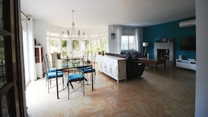 A spacious living area with a dining table and chairs, a sofa, and a fireplace.