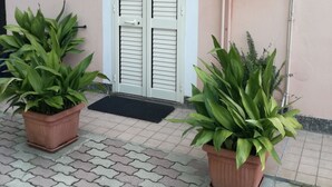 Entrada de un edificio con puertas dobles, un pequeño toldo y dos macetas.