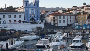 A marina with various boats docked, a prominent blue building with a clock tower, and colorful buildings in the background. - Traditional Angra House (Angra do Heroísmo)