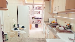 A compact kitchen with a refrigerator, microwave, sink, and a small dining area with a table and chairs. - Apartment 2 rooms for rent for more than 10 days with free parking. (València)