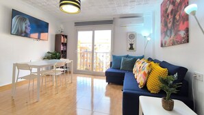 A living room with a sofa, a dining table with chairs, a TV, and a balcony with a view. - Apartment 2 rooms for rent for more than 10 days with free parking. (València)