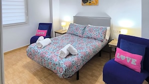 A bedroom with a bed, two chairs, a painting, and a ceiling light. - Apartment 2 rooms for rent for more than 10 days with free parking. (València)
