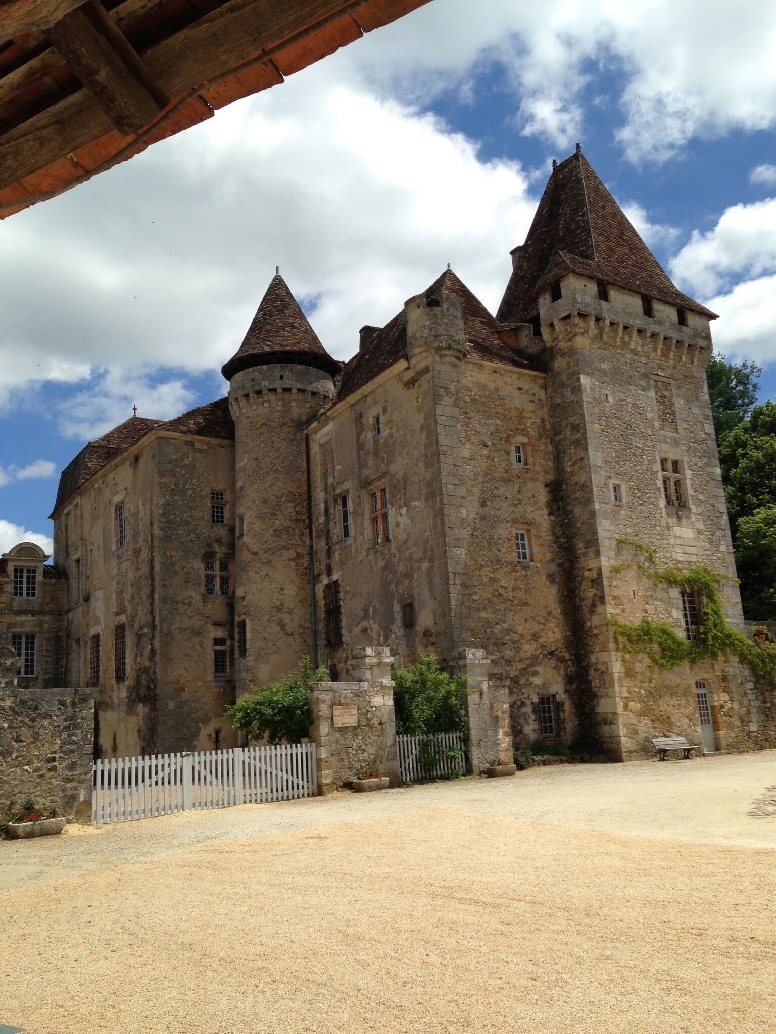A historic stone castle with multiple towers and a white picket fence in front.