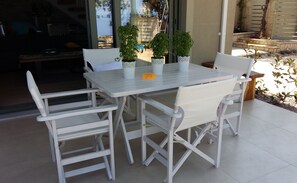 Une table en métal blanc, accompagnée de quatre chaises, entourée de plantes en pot.