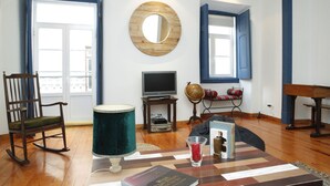 Un salon avec un fauteuil à bascule en bois, un globe terrestre, un téléviseur et un piano.