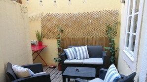 Un espace extérieur accueillant, aménagé avec des meubles en osier, une petite table et des guirlandes lumineuses.
