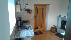 Une cuisine de taille réduite, équipée d’une cuisinière à gaz, d’un évier et d’une porte en bois.