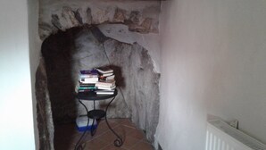 Un étroit arc en pierre mène à une petite pièce dont le sol est recouvert de carreaux. Une petite table noire, sous laquelle se trouve un récipient bleu, est placée contre le mur.
