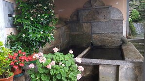 Un puits en pierre, avec un muret en pierre et un petit élément décoratif aquatique.