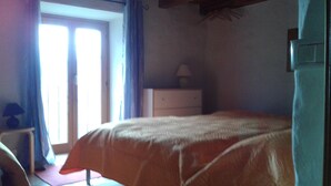 Une chambre à coucher avec un lit, une commode et une fenêtre avec des rideaux.