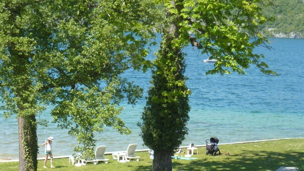 A lakeside deck with chairs and a small bridge over a water feature.