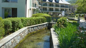 A hotel with multiple balconies, a stone-lined canal, and lush greenery.
