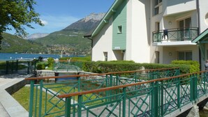 A hotel with a balcony overlooking a lake, a mountain in the background, and a small pool area.