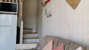 A cozy room with a bed, a heart-shaped mirror, a white refrigerator, and a staircase leading to another level.