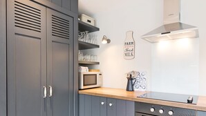 Una cocina moderna con gabinetes grises, un microondas, una estufa y una lámpara en la pared.