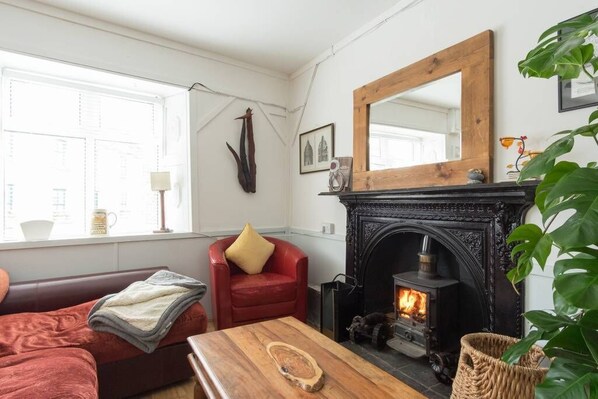 A cozy living room with a fireplace, a red armchair, a wooden coffee table, and a large mirror on the wall. - Charming Kinvara Cottage, Walk to bay,Parking,Cliffs of Moher &Wild Atlantic Way (Kinvara)