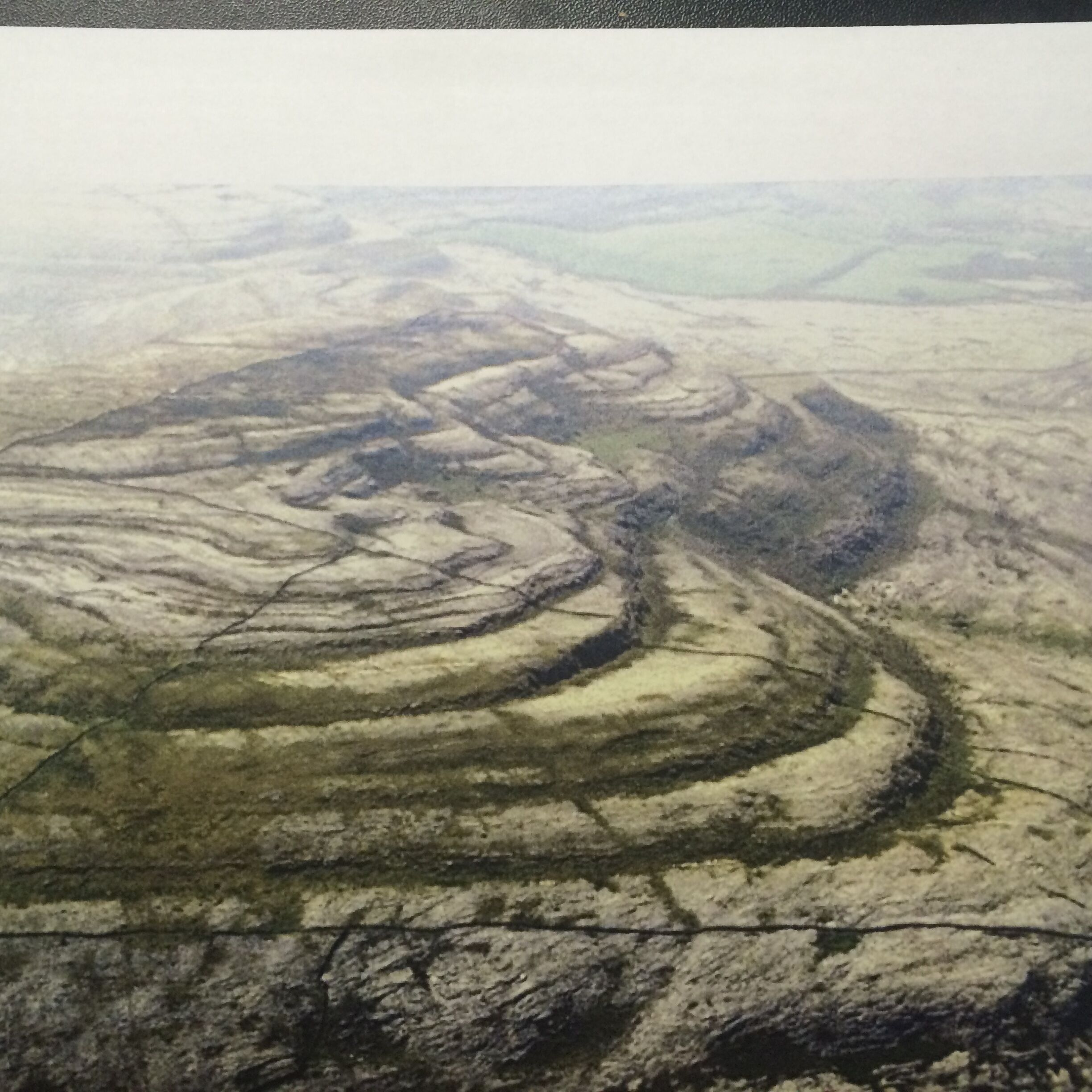 A vast, undulating landscape with concentric ridges and valleys, likely a natural geological formation.