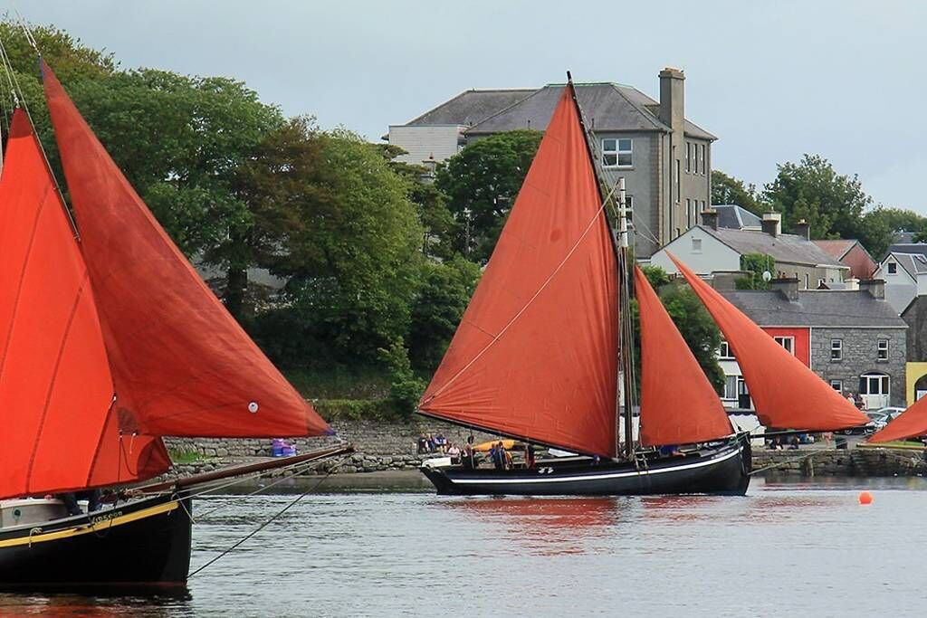Un port avec des voiliers, une eau calme et des bâtiments en arrière-plan.