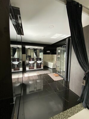 A modern bathroom with a large mirror, two sinks, a bathtub, and a glass shower enclosure.