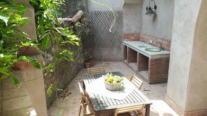 Un petit espace de cuisine extérieur comprenant une table, des chaises et un évier.