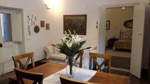 Un coin repas avec une table et des chaises en bois, un vase rempli de fleurs et un tableau accroché au mur.