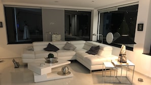Un salon moderne avec un canapé d’angle blanc, une table basse et un lampadaire.