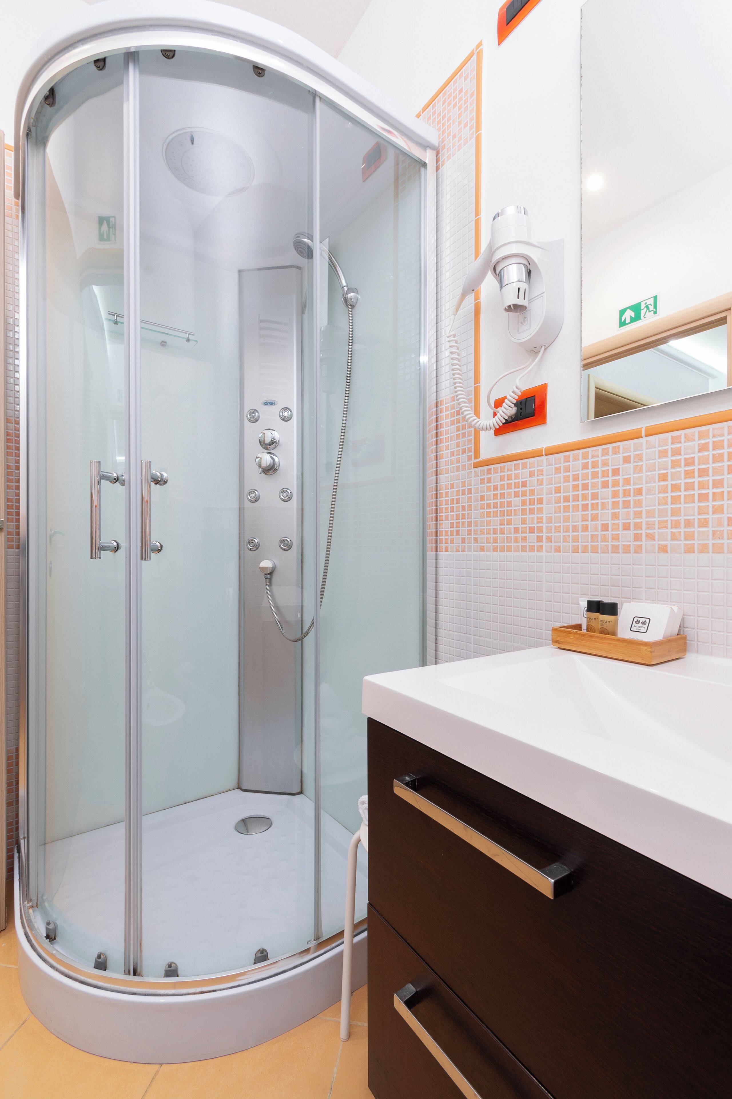 A modern bathroom with a glass-enclosed shower, a white sink, and a wooden vanity.