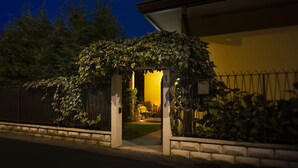 A house with a covered entrance, a visible number '1' on the wall, and a small garden area with a bench and a table.