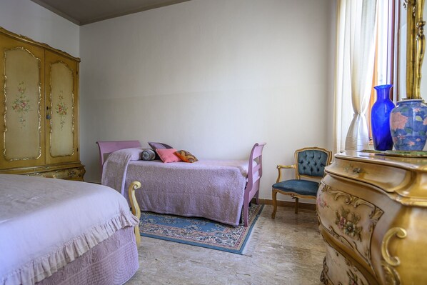 Un dormitorio con cama, una silla, cómoda y espejo.