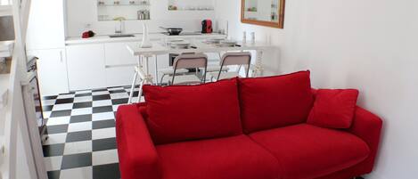 A red sofa in a room with a checkered floor and white walls.