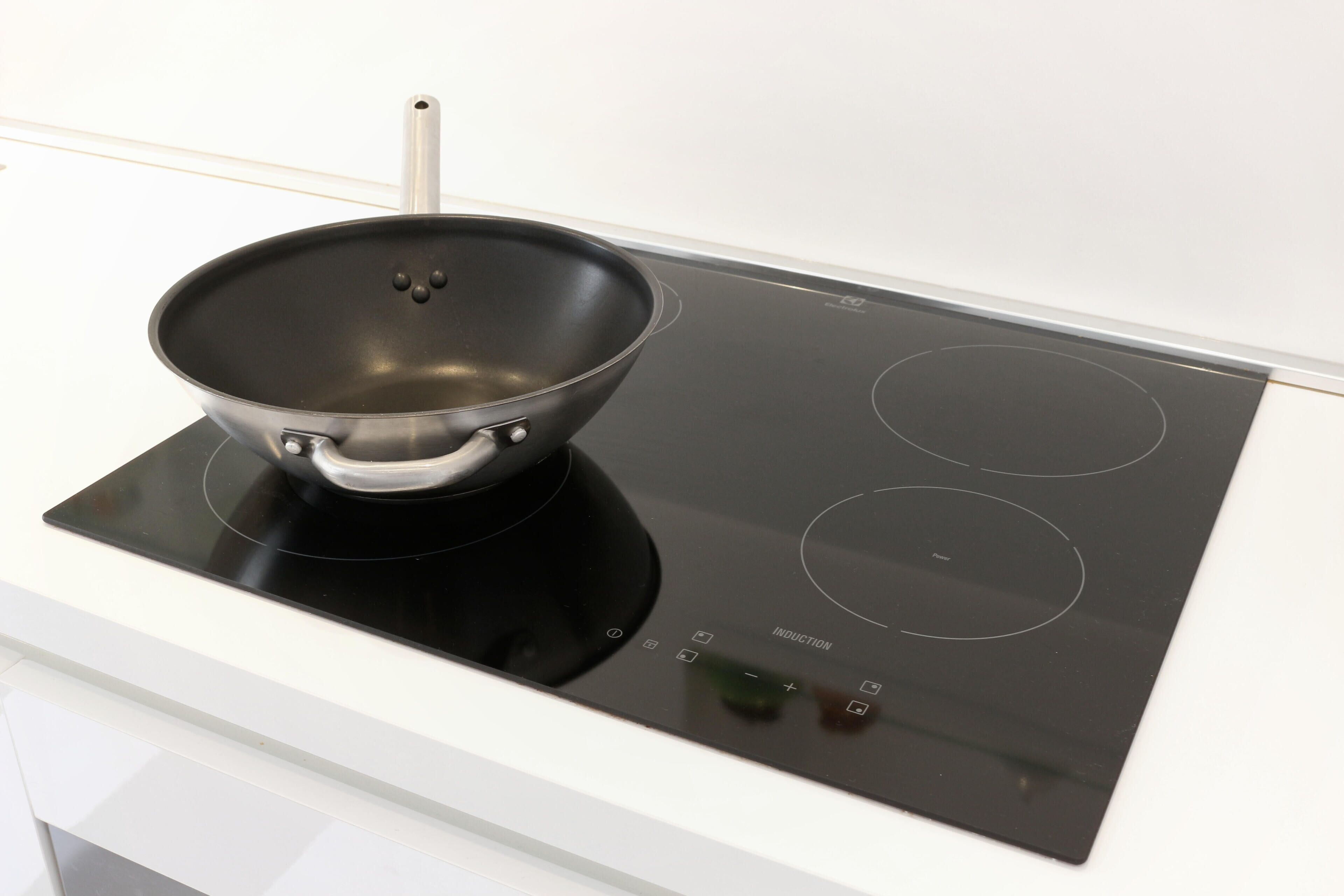Una cuina d'inducció moderna amb una paella negra a sobre.